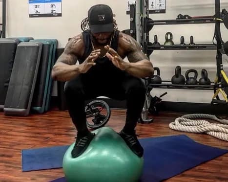 Athlete balancing in a squat on a stability ball during sports performance training